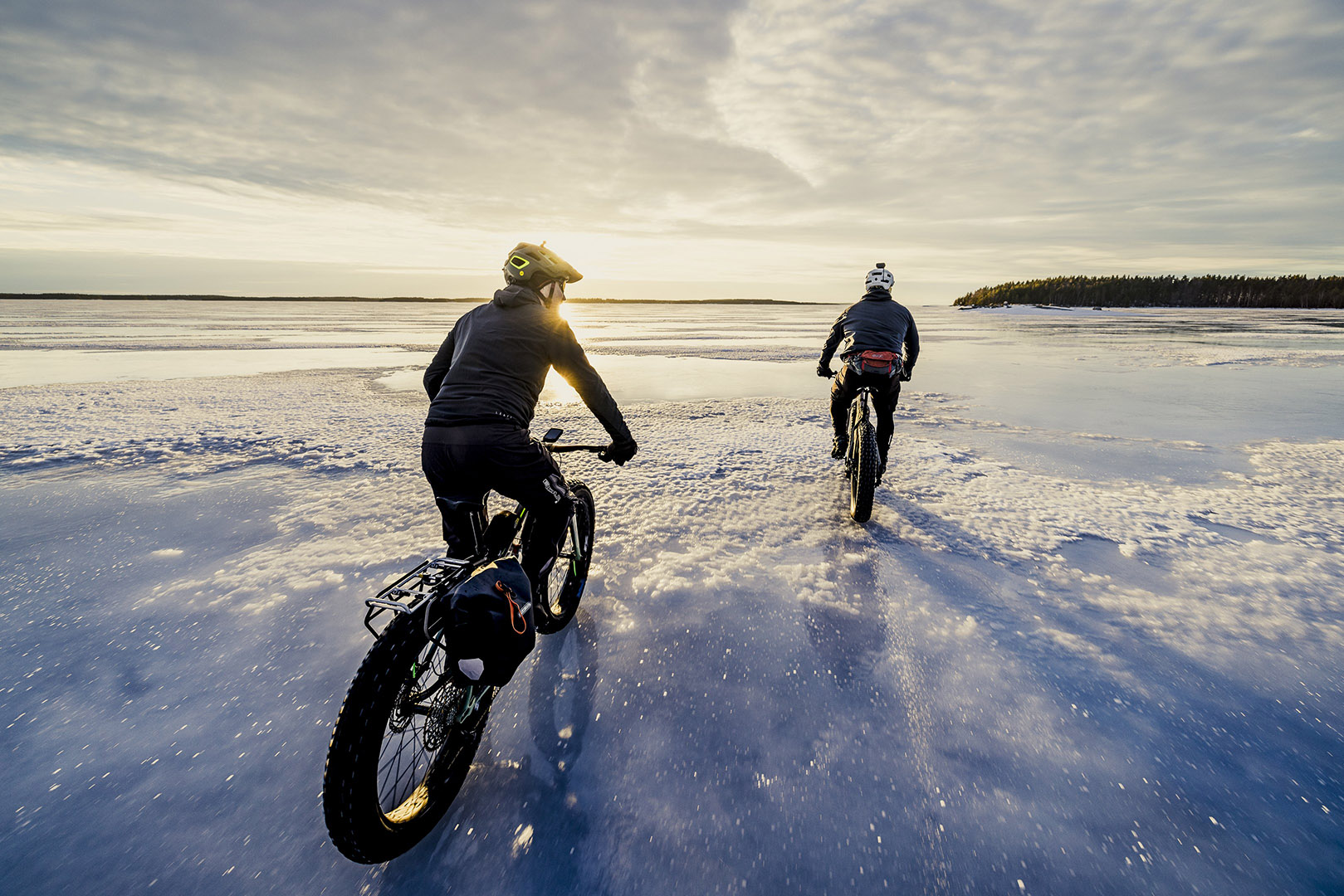 Kaksi pyöräilijää ajamassa järven jäällä.